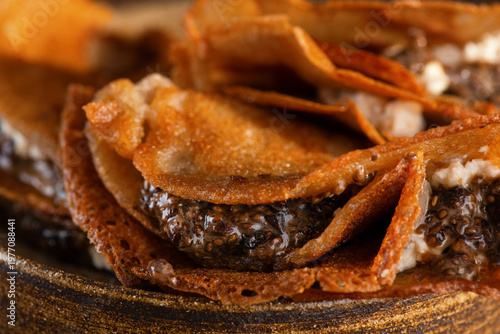 Thin gluten-free crepes with vegan cashew ricotta filling and chia seed caviar, close-up. Thin pancakes made from banana flour.