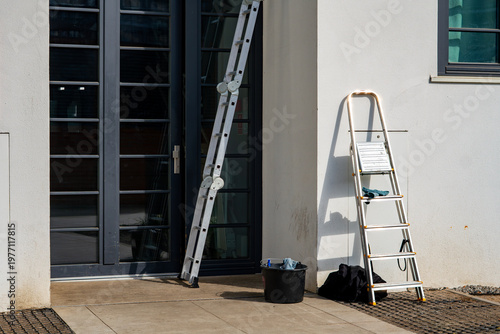 Schilderij op canvas Aluminum multi-purpose ladder and stepladder leaning against a white modern buil