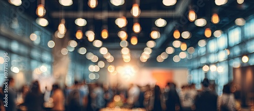 Blurred indoor event with numerous people and warm, glowing bokeh lights