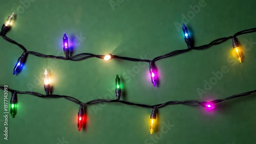 String of colorful christmas lights with red green blue yellow and purple bulbs on a green background