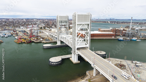 Aerial view of the iconic Fore River Bridge cutting through the waters, its stark white structure contrasting against the muted greens and blues, Quincy, Massachusetts, United States.