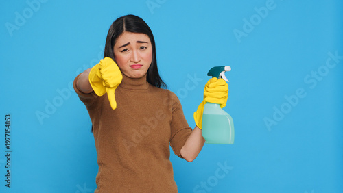 Fotografía Upset unhappy housekeeper holding hygiene detergent spray doing disapproval sign studio