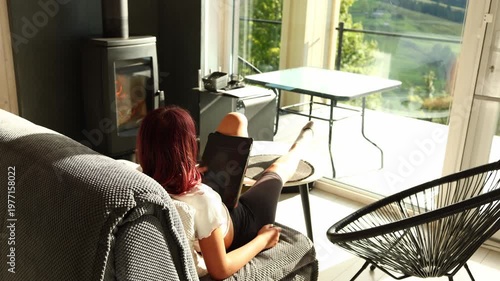 Girl sitting on couch looking at tablet while resting leg on table in modern living room