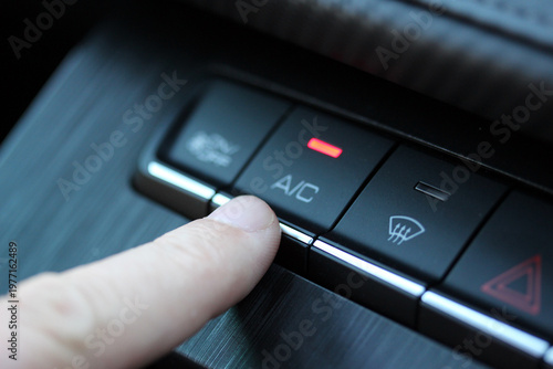 Close up of a finger pressing the A/C button in a modern vehicle