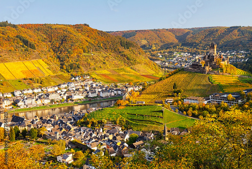 Scenic autumn view of a river valley with vineyards, colorful hills, and  charming town Cochem in warm golden light, Rhineland-Palatinate, Germany.