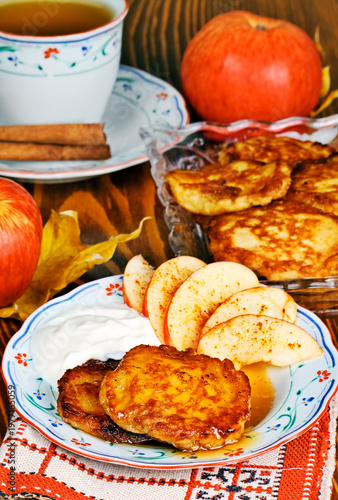 Homemade fried pancakes served with honey, sour cream and slices of apple for breakfast.