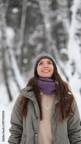 Canvastavla A beautiful young woman in winter clothes is happily spending her free time in a snowy forest