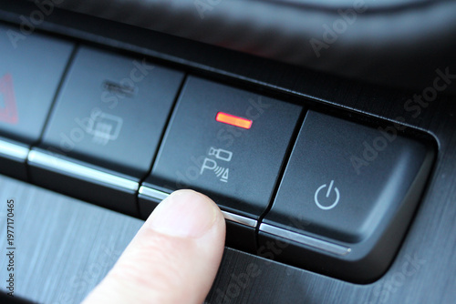 Finger pressing a camera button on a modern vehicle dashboard