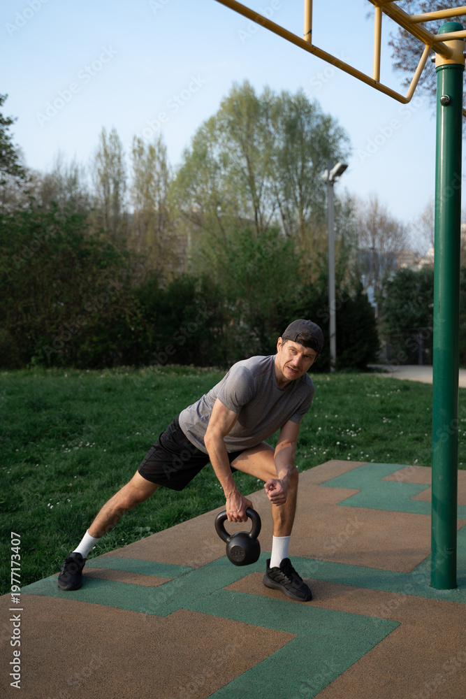 Obraz premium Man Training with 16 kg Kettlebell at Outdoor work out Area