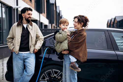 Family with child charging their electric vehicle on a residential street, promoting sustainable transportation and modern living