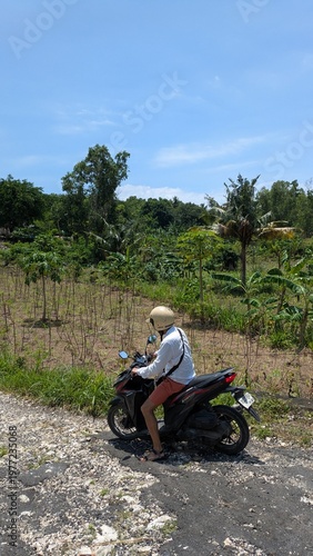 Man riding motorbike through tropical countryside in Bali Indonesia, offroad adventure on dirt trail and rocky mountain road, solo traveler enjoying freedom journey, extreme outdoor travel and scooter