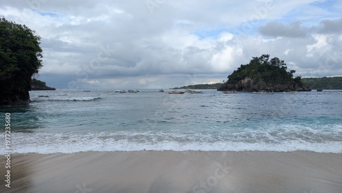Photos Tropical beach with a green island and traditional boats on turquoise water, sce