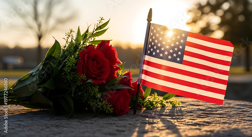 American flag on a grave with a bouquet of pink and red roses in a garden setting