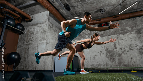 Man and woman performing functional training movement with forward reach in gym. Concept of mobility training, balance development, fitness program and athletic performance