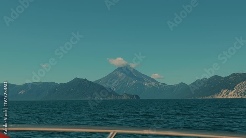 Stunningly beautiful view from yacht of mountain ranges on coast and majestic volcano with peak in clouds. Concept of freedom and pacification