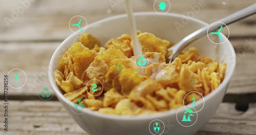 Vertical video: Milk pouring into bowl on table splashing cereal, teal eco icons drifting for meal