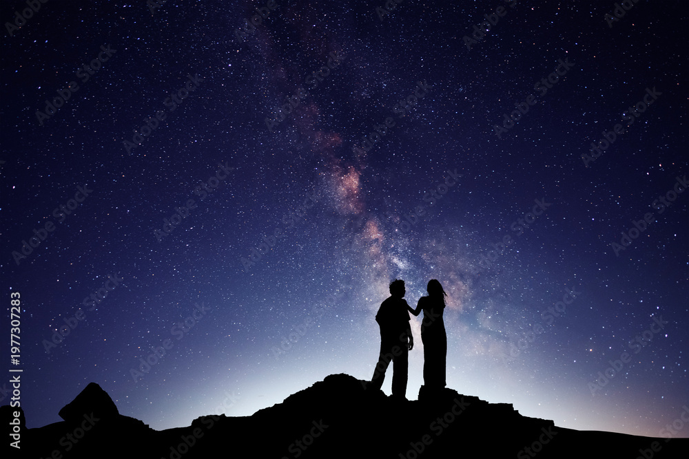 Fototapeta premium Silhouettes of lovers against the backdrop of the colorful Milky Way galaxy.
