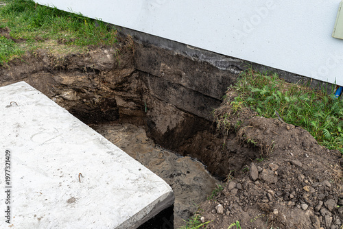 фотографія House foundation undermining with exposed soil and water
