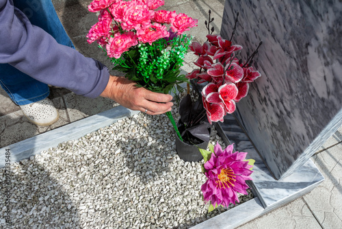 Hands placing artificial flowers on a grave