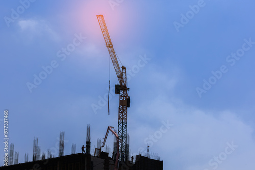 Construction crane and workers operating concrete pump on building site under dramatic sky, representing urban development and infrastructure growth.