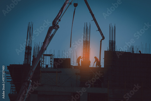Silhouette of construction workers and concrete pump operating on building site during sunset, representing teamwork, engineering process and urban development.