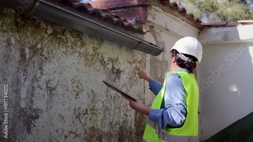 Foto Engineer inspecting exterior house wall for water damage, checking for mold grow