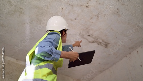 Tableau sur toile Building inspector wearing hard hat and safety vest evaluating ceiling damage, p