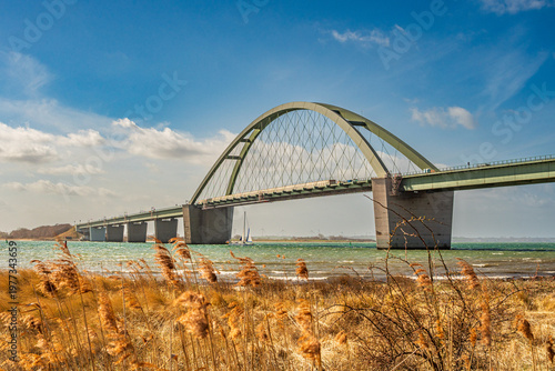 Die Fehmarnsundbrücke auf der Ostseeinsel Fehmarn im Frühling mit Segelboot unter der Brücke