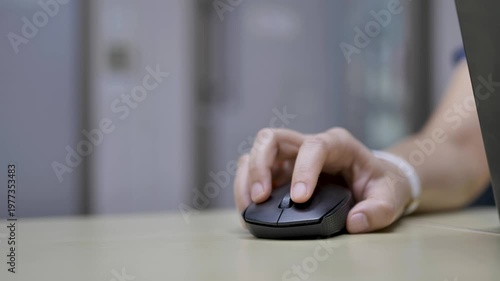 Close-up of a hand using a computer mouse on a desk. Suitable for technology, work, and everyday office activity themes.