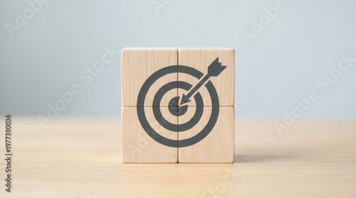 Darts target aim icon on wooden cubes symbolizes business goals and strategic planning for achieving success, set against a grey background with ample copy space.