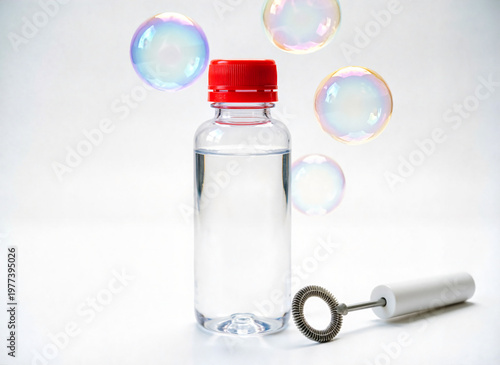 plastic bottle of bubble solution anda round bubble wand on white