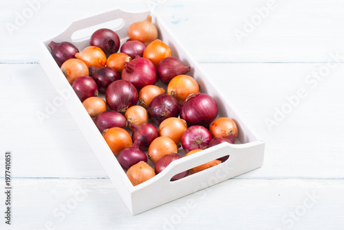 onions on white wood tray, wooden table background