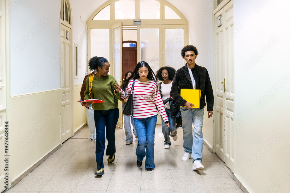 Obraz premium Diverse group of high school or college students walking and communicating in an educational building corridor