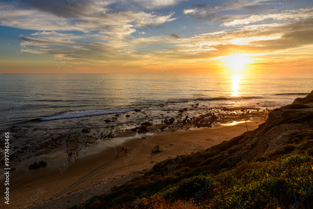 Obraz premium Gentle waves rolling onto the shore at Crystal Cove during dusk 