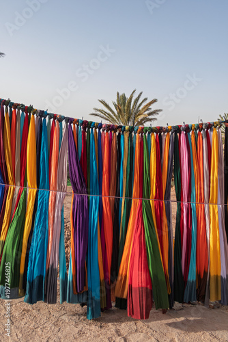 Colorful scarves hanging in moroccan desert with palm tree