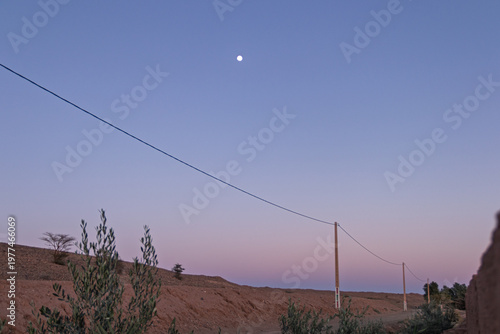 Desert sunset sky with moon and power lines