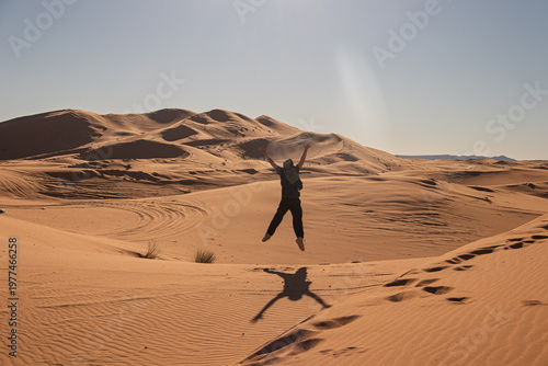 Person jumping in sahara desert feeling joy and freedom