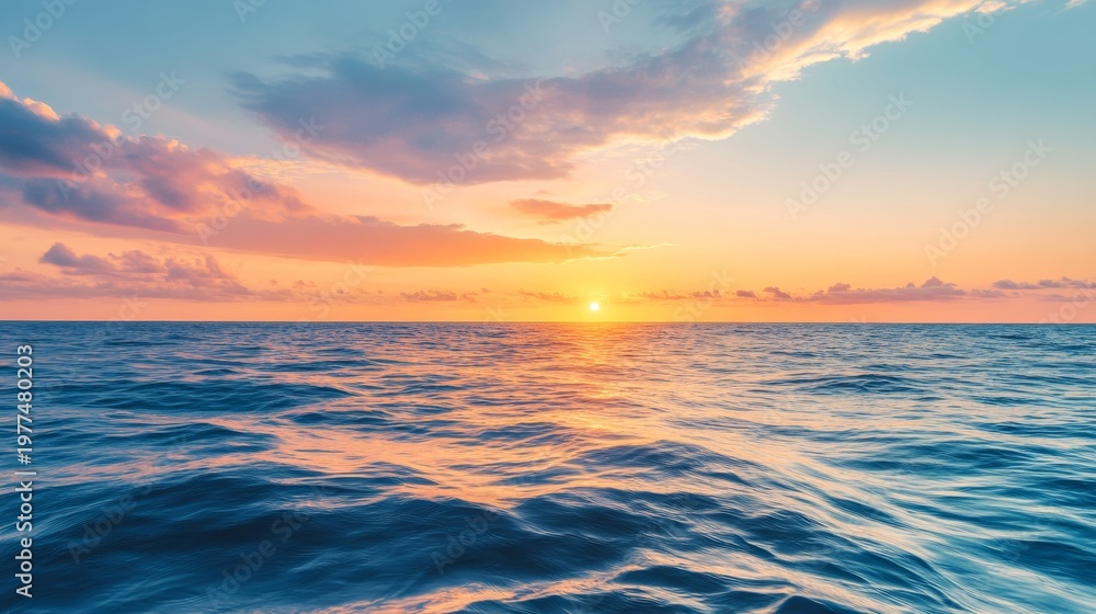 Naklejka premium Sun rises over calm ocean waves at dawn with colorful clouds in the sky