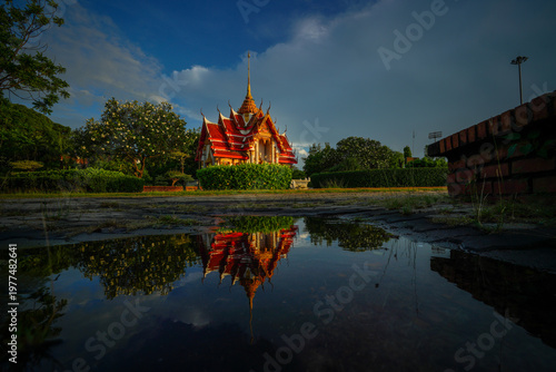 A beautiful Thai temple reflected in a rain puddle.