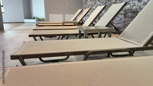 Poolside loungers and table near brick wall in a modern indoor setting, perfect for relaxation