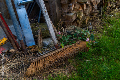 Aufnahme von einem Besen, abgestellt vor einem Holzstabel.