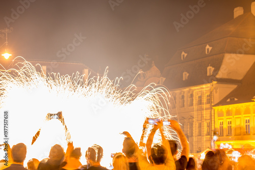 Long exposure motion blurred photograph. SIBIU, ROMANIA: People are watching a firework display in a city square