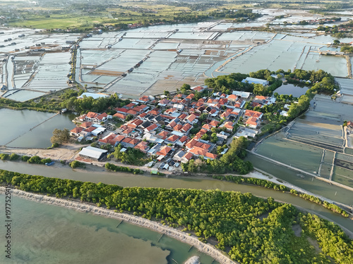 Aerial view of coastal village with red rooftops surrounded by salt ponds and waterways landscape