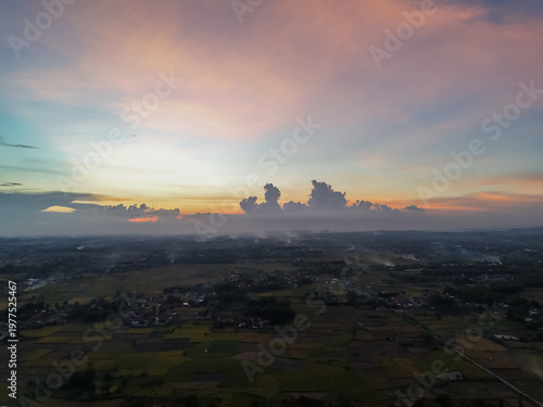 Aerial sunset skyover rural farmland landscape with misty fields and colorful sky horizon