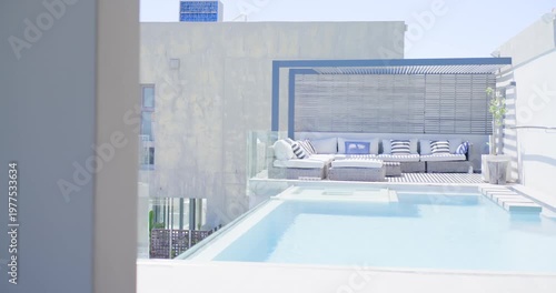 Camera panning from left, revealing rooftop pool with shallow ledge, steps, sectional sofa