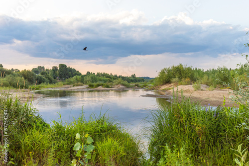 Serene river landscape with lush greenery and dramatic cloud formations