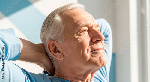 Elderly man stretching back outdoors in the sunlight to relieve muscle tension. Active retirement and senior outdoor fitness.