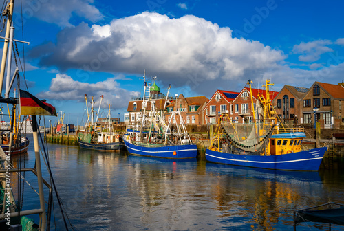 An idyllic, sunny evening atmosphere in Neuharlingersiel, a small, picturesque fishing village with brick houses on the German North Sea coast. From there, ferries depart to Spiekeroog island.