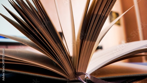 Open book with pages fanned out on desk in modern room
