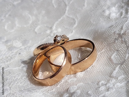 Elegant gold wedding rings on white lace fabric background